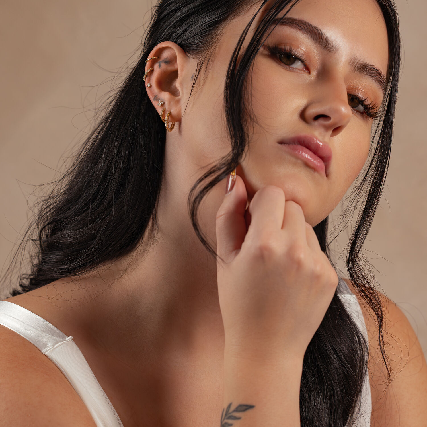 Frau mit 14K Gold Moissanit Aufsatz im Ohr auf neutralem Hintergrund