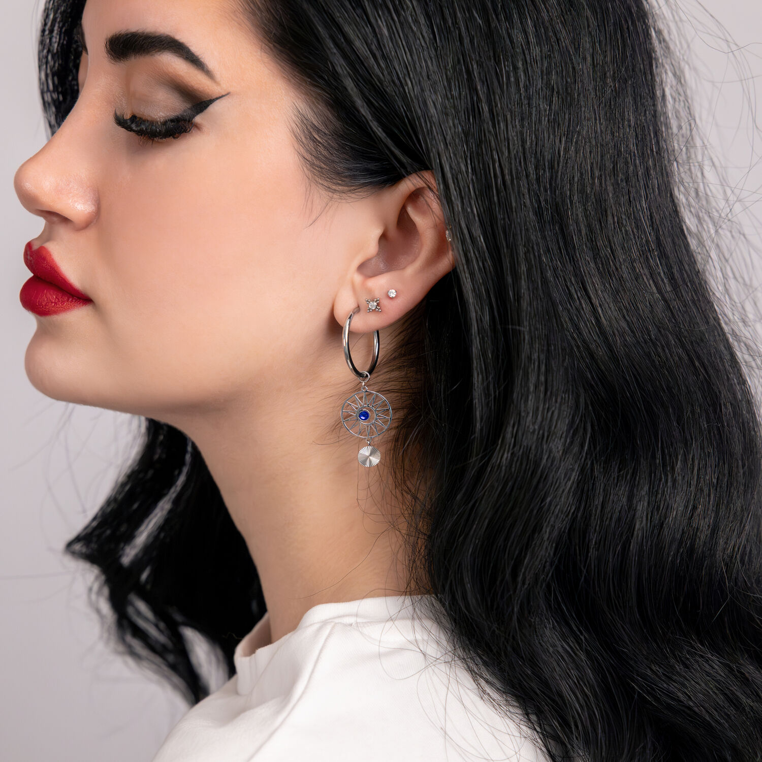 Frau trägt silberne und goldene Creolen mit dunkelblauen Kristallen