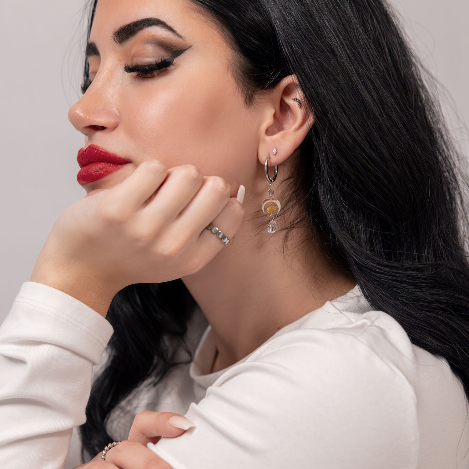 Frau mit langen schwarzen Haaren trägt silberne Edelstahl-Ohrhänger vor neutralem Hintergrund