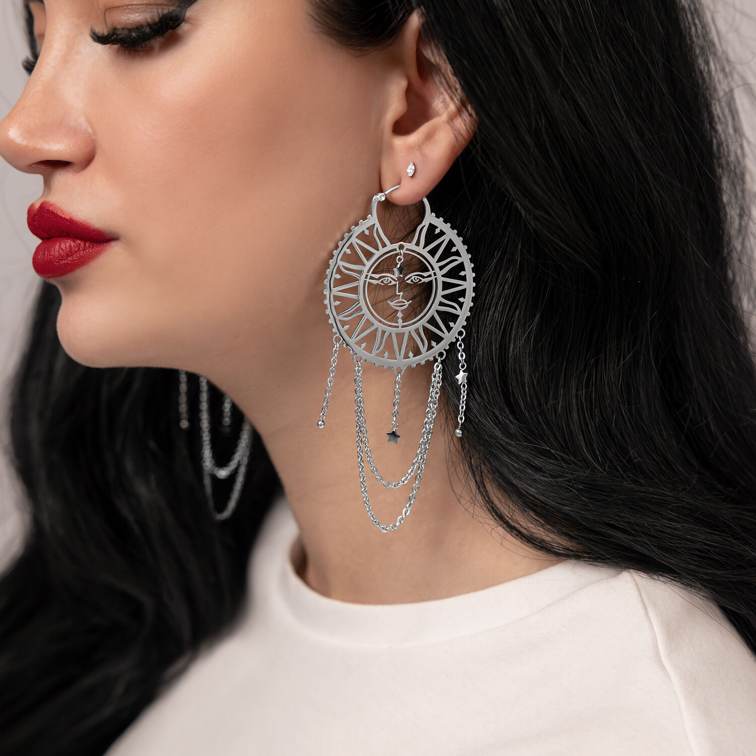 Silberne Ohrringe mit Sonne-Mond-Design an Frau mit dunklen Haaren